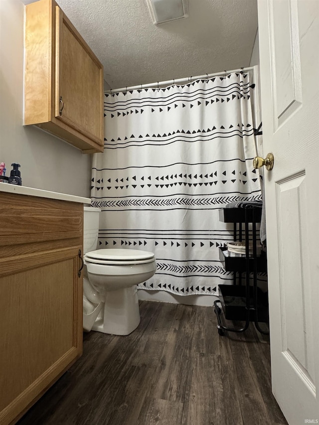 bathroom with wood-type flooring, walk in shower, a textured ceiling, and toilet