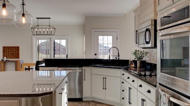 kitchen featuring sink, decorative light fixtures, ornamental molding, stainless steel appliances, and white cabinets