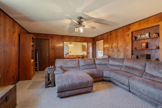 living room featuring ceiling fan, a textured ceiling, carpet, and wood walls