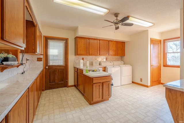 kitchen featuring ceiling fan, washing machine and clothes dryer, sink, and decorative backsplash