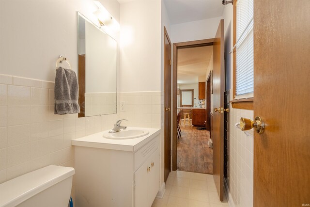 bathroom with tile walls, vanity, and toilet