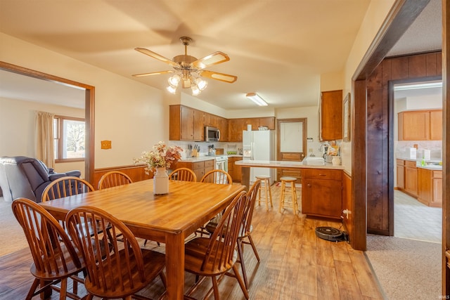 dining space with ceiling fan and light wood-type flooring