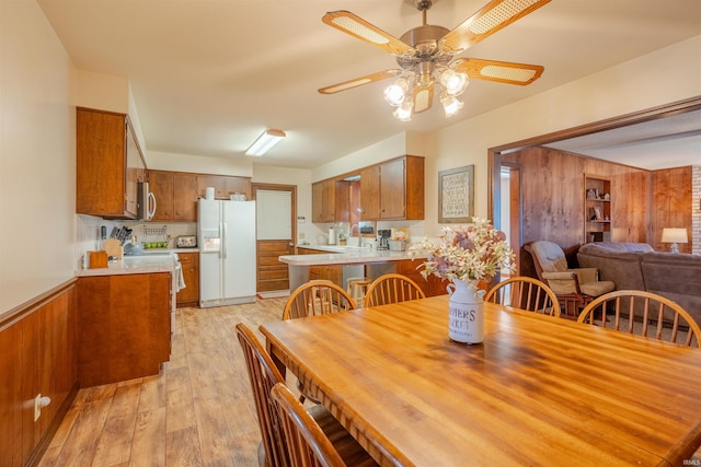 dining room with ceiling fan, wooden walls, and light hardwood / wood-style flooring