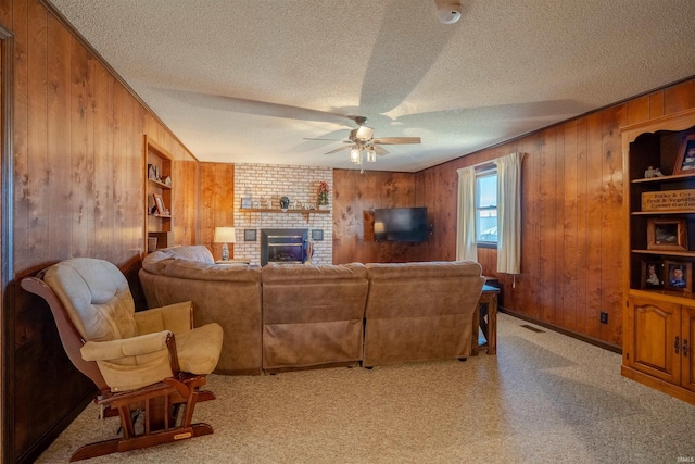 living room featuring ceiling fan, a fireplace, light carpet, and a textured ceiling