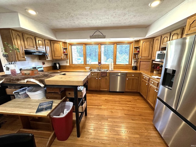 kitchen featuring appliances with stainless steel finishes, sink, light hardwood / wood-style flooring, and a textured ceiling