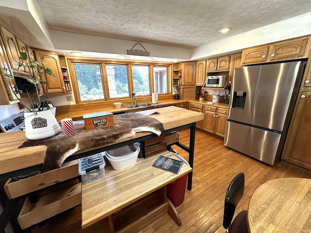 kitchen with sink, light wood-type flooring, a textured ceiling, and appliances with stainless steel finishes