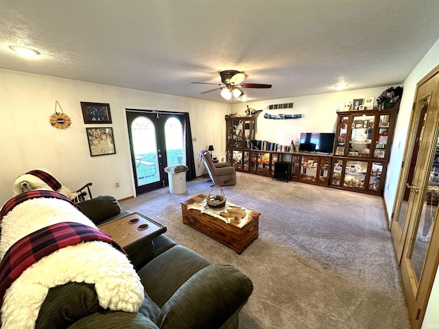 carpeted living room featuring ceiling fan, french doors, and a textured ceiling