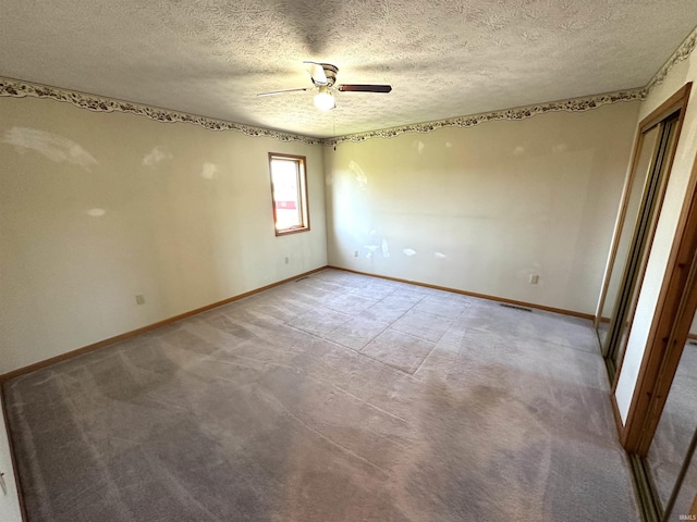 spare room featuring ceiling fan, light colored carpet, and a textured ceiling