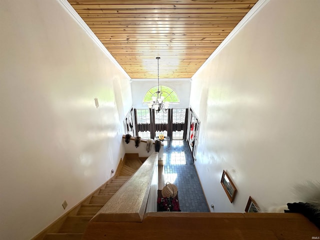 corridor with crown molding, an inviting chandelier, and wooden ceiling