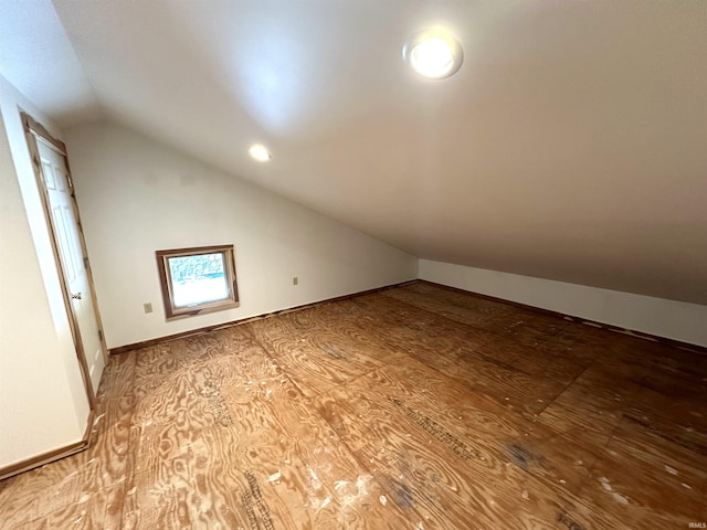 additional living space with hardwood / wood-style flooring and vaulted ceiling