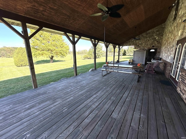 wooden terrace featuring ceiling fan and a yard