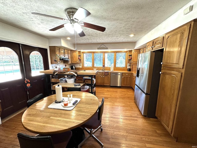 dining room with a textured ceiling, ceiling fan, and light hardwood / wood-style flooring