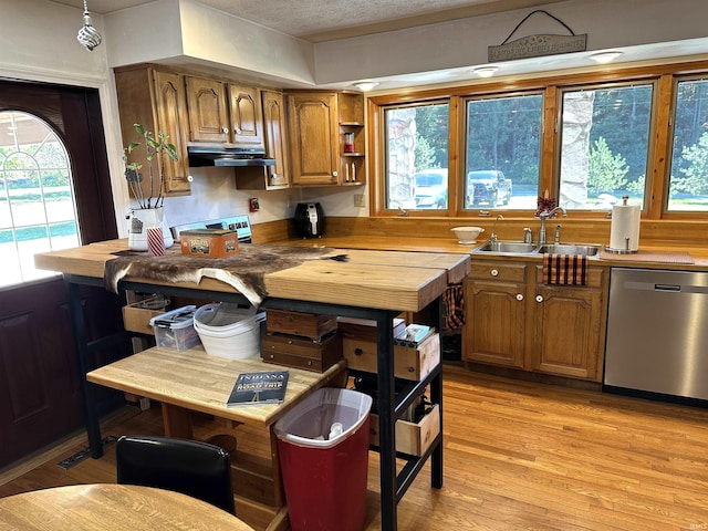 kitchen with appliances with stainless steel finishes, sink, a textured ceiling, and light wood-type flooring