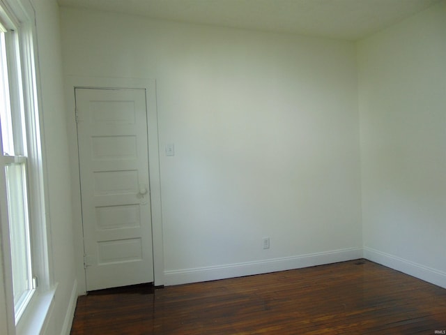 spare room featuring a healthy amount of sunlight and dark hardwood / wood-style floors