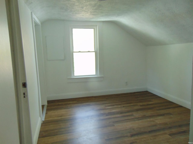 bonus room featuring dark wood-type flooring, vaulted ceiling, and a textured ceiling