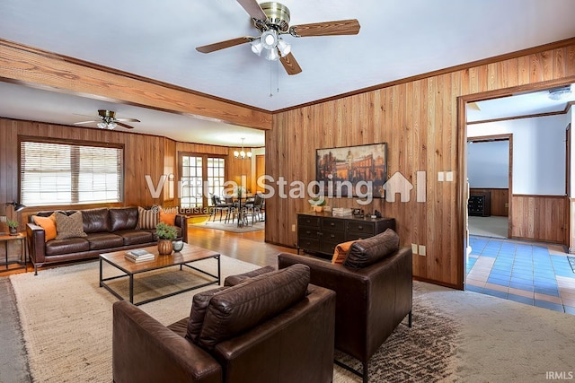 living room featuring crown molding, ceiling fan with notable chandelier, and wood walls