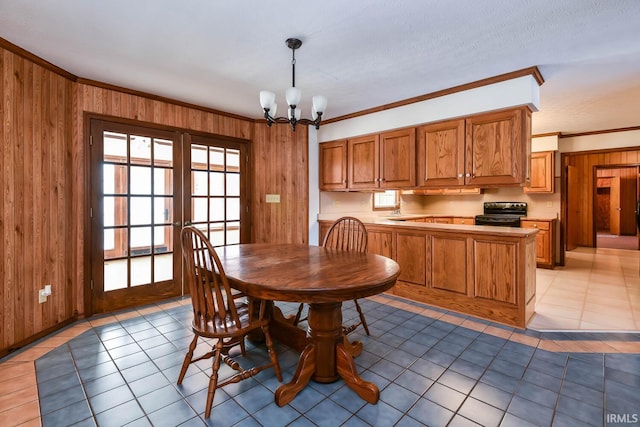 tiled dining space with ornamental molding, wooden walls, and an inviting chandelier