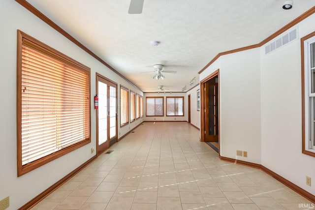 corridor with ornamental molding, a textured ceiling, and light tile patterned floors