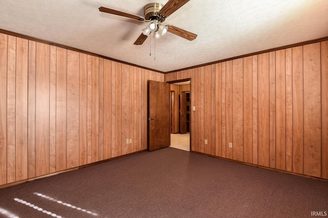 empty room featuring ornamental molding, wooden walls, and a textured ceiling