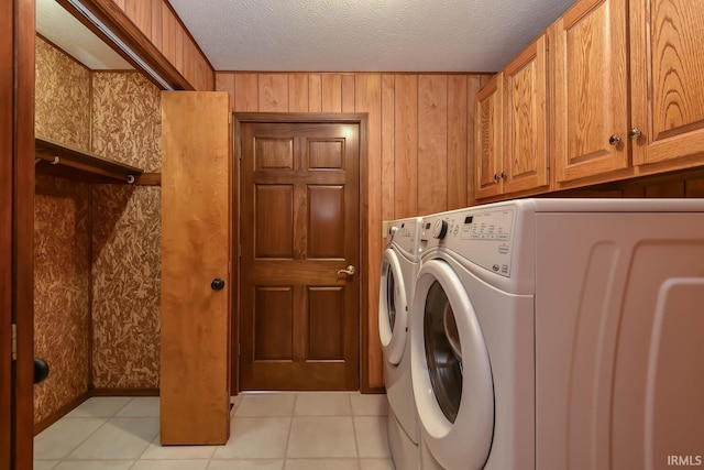 washroom featuring cabinets, washing machine and clothes dryer, light tile patterned flooring, and a textured ceiling