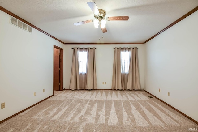 spare room with crown molding, light colored carpet, and a textured ceiling