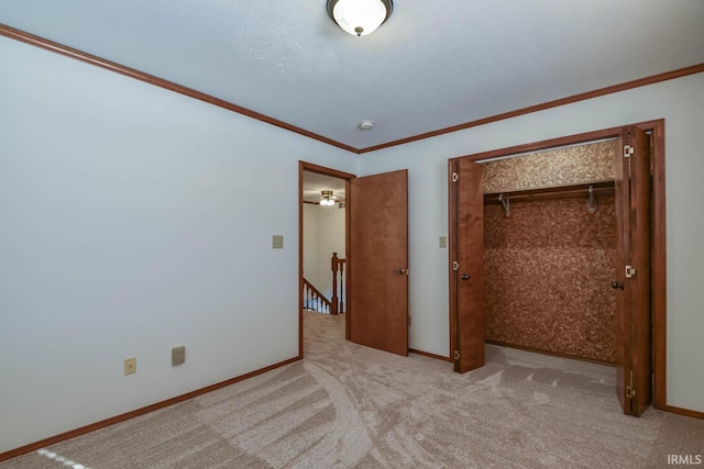 unfurnished bedroom with light colored carpet, ornamental molding, a closet, and a textured ceiling