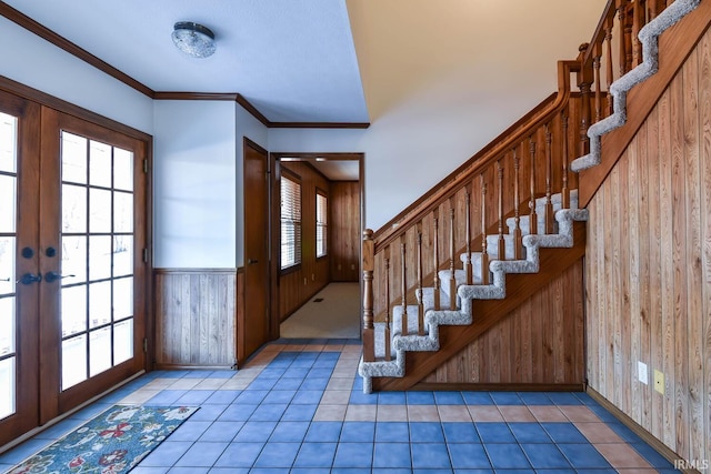 foyer featuring tile patterned flooring, ornamental molding, french doors, and wood walls