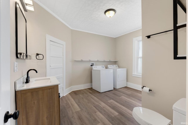 bathroom featuring toilet, crown molding, vanity, washer and clothes dryer, and hardwood / wood-style floors