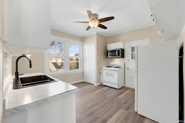 kitchen with sink, white cabinets, ornamental molding, white appliances, and light hardwood / wood-style flooring