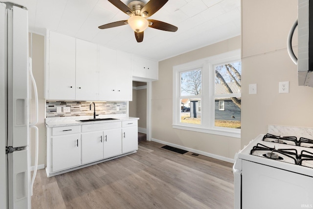 kitchen featuring sink, white appliances, white cabinetry, decorative backsplash, and light wood-type flooring