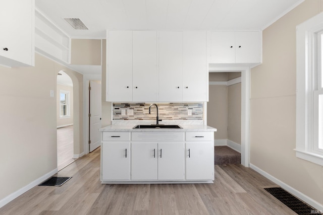 kitchen featuring white cabinetry, sink, light wood-type flooring, and decorative backsplash