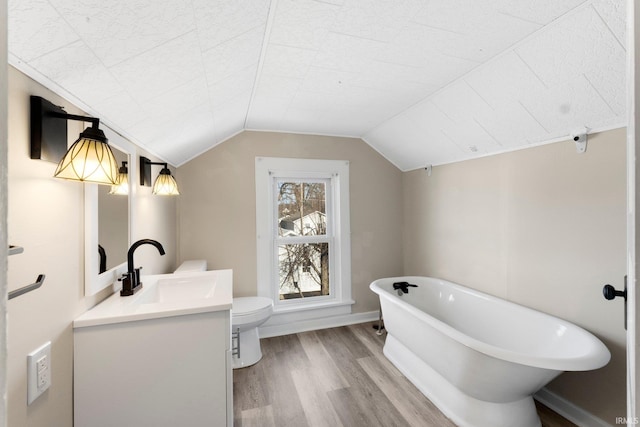 bathroom with toilet, vaulted ceiling, vanity, a bathtub, and hardwood / wood-style flooring