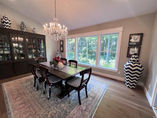 dining space featuring hardwood / wood-style flooring, lofted ceiling, and a notable chandelier