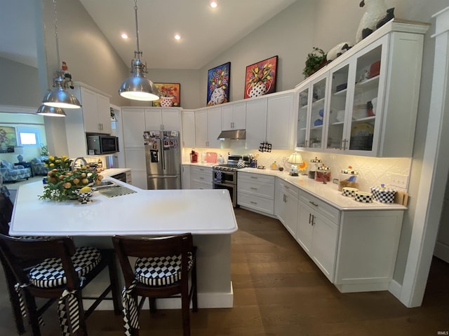 kitchen with a kitchen bar, decorative light fixtures, high vaulted ceiling, appliances with stainless steel finishes, and white cabinets