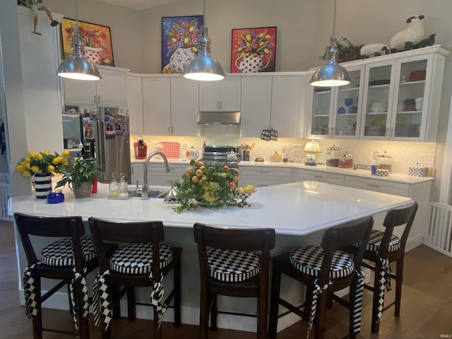 kitchen with sink, white cabinetry, a kitchen breakfast bar, stainless steel appliances, and decorative backsplash