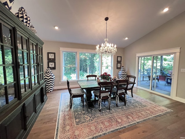 dining space with an inviting chandelier, hardwood / wood-style floors, and vaulted ceiling