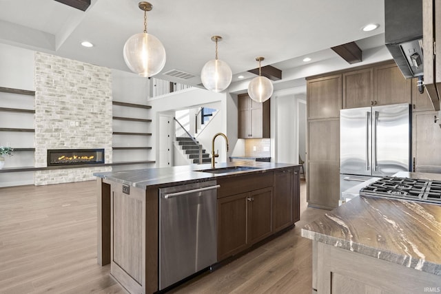 kitchen with sink, a center island with sink, hanging light fixtures, and appliances with stainless steel finishes