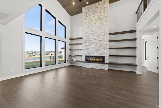 unfurnished living room featuring dark hardwood / wood-style floors, a large fireplace, wood ceiling, and a towering ceiling