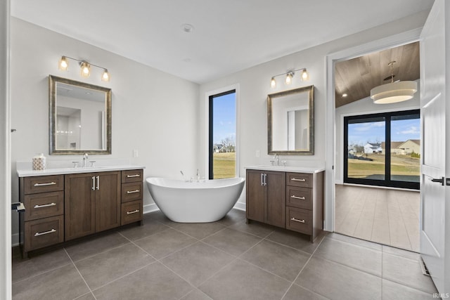 bathroom featuring tile patterned flooring, vanity, plenty of natural light, and a tub to relax in