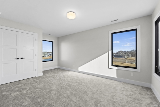 unfurnished bedroom featuring light colored carpet and a closet