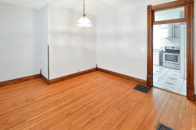 spare room with hardwood / wood-style floors and an inviting chandelier