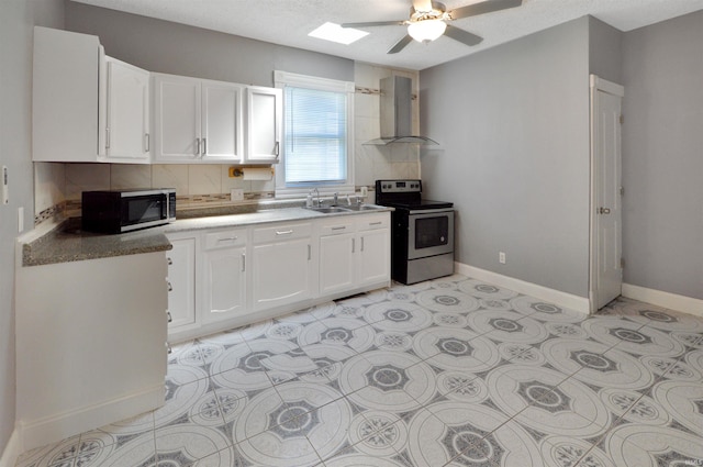 kitchen with sink, ceiling fan, appliances with stainless steel finishes, white cabinets, and wall chimney exhaust hood