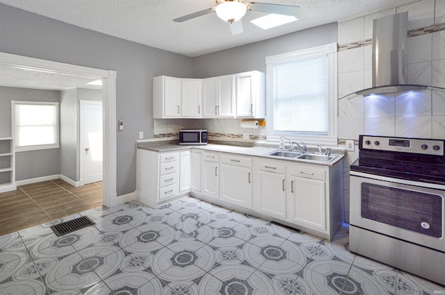 kitchen with wall chimney range hood, sink, appliances with stainless steel finishes, a textured ceiling, and white cabinets