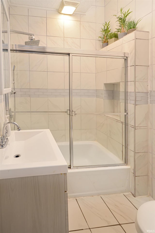 full bathroom featuring vanity, shower / bath combination with glass door, and toilet