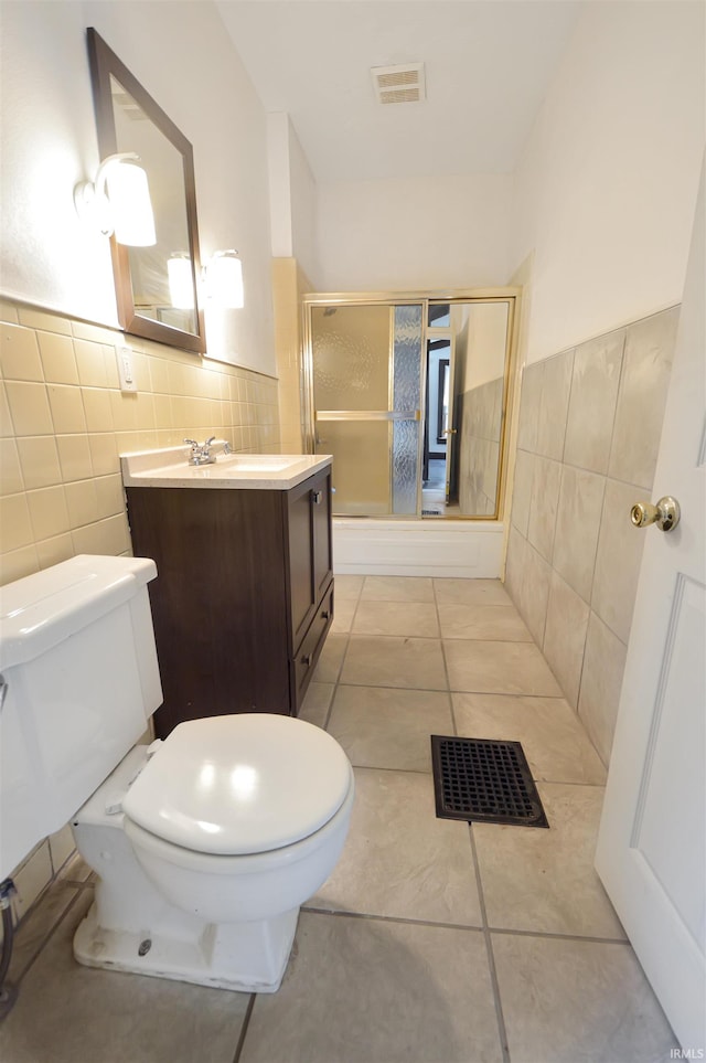 bathroom featuring tile walls, tile patterned flooring, a shower with shower door, and toilet