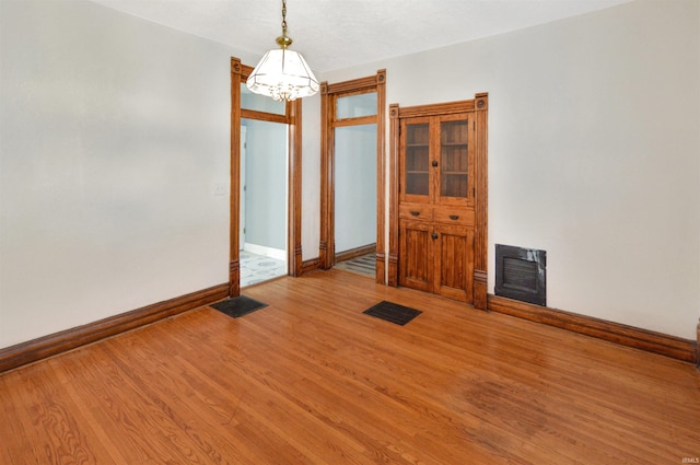 spare room featuring wood-type flooring and a notable chandelier