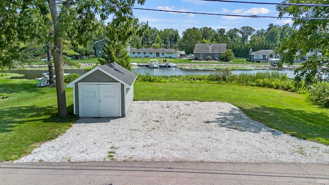 view of property's community featuring a lawn, a storage unit, and a water view