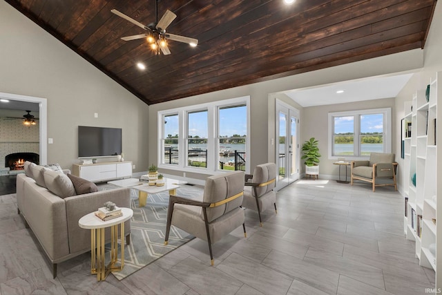 living room with ceiling fan, high vaulted ceiling, wooden ceiling, and a fireplace