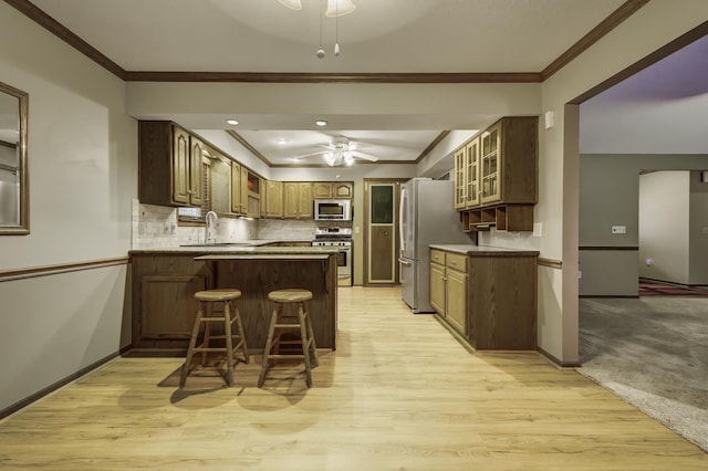 kitchen featuring sink, ornamental molding, kitchen peninsula, ceiling fan, and stainless steel appliances