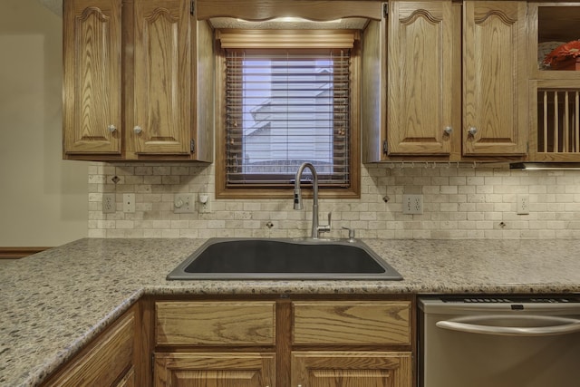 kitchen featuring dishwasher, sink, light stone countertops, and backsplash